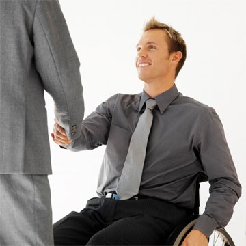 Man in wheelchair shakes hand with another man.